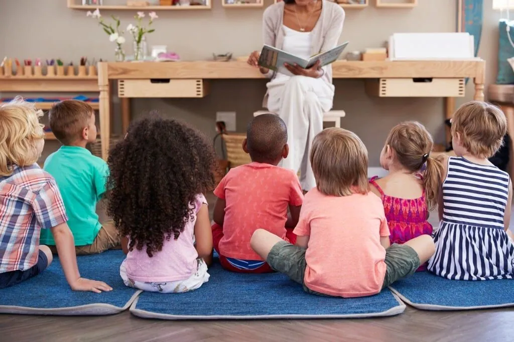 Montessori teacher reading to engaged children during story time in classroom setting
